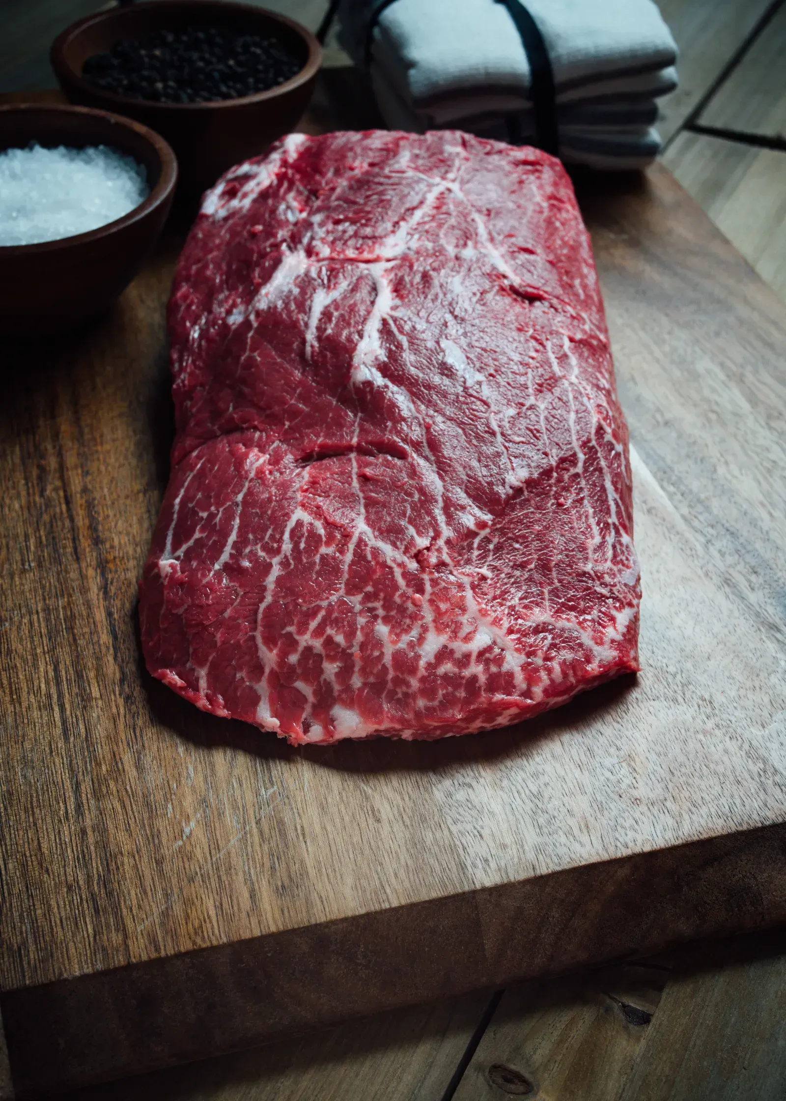 Thomas Cattle rib steak with seasoning bowls on butcher board.