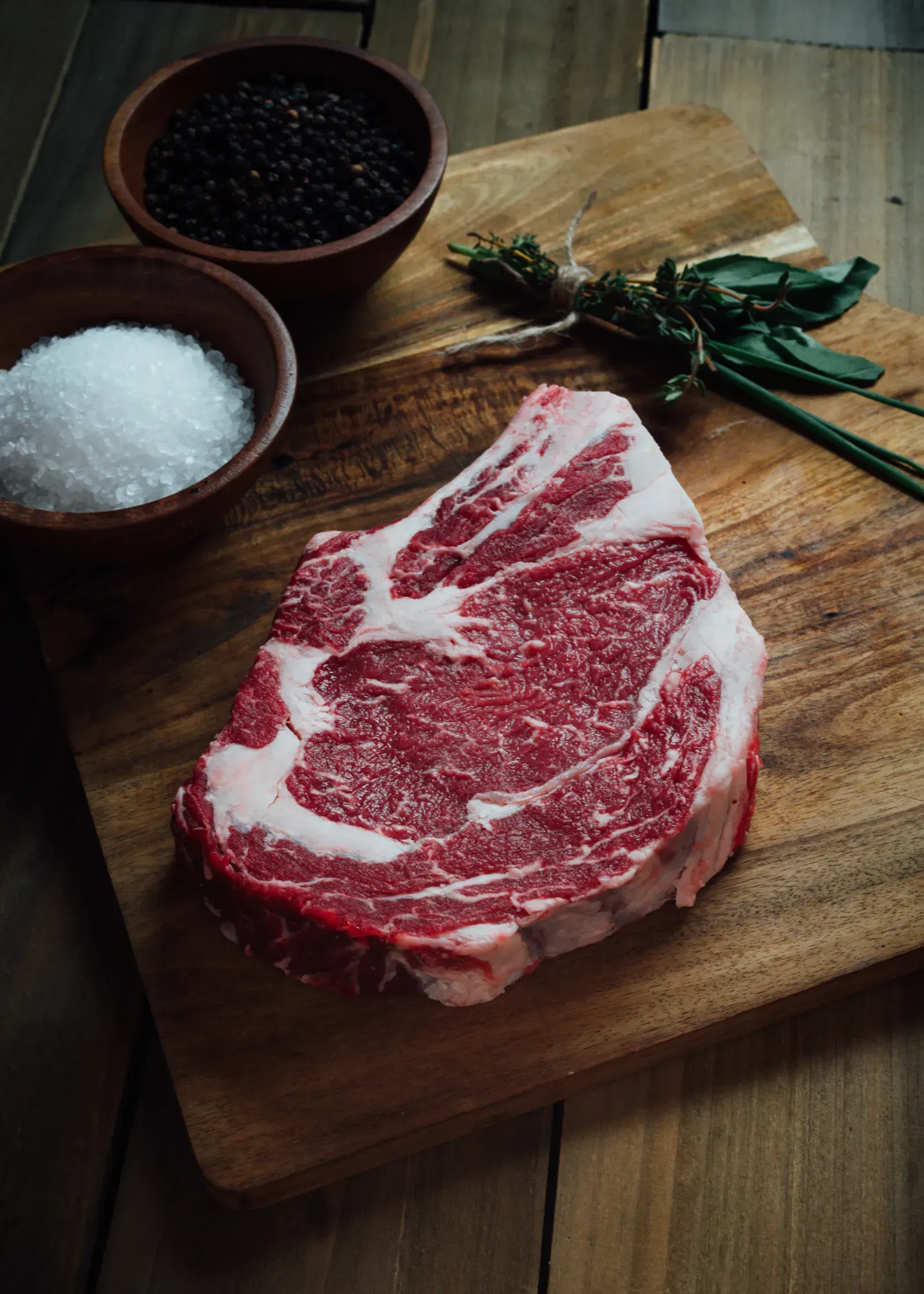 Fresh steak cuts displayed on wooden butcher block.