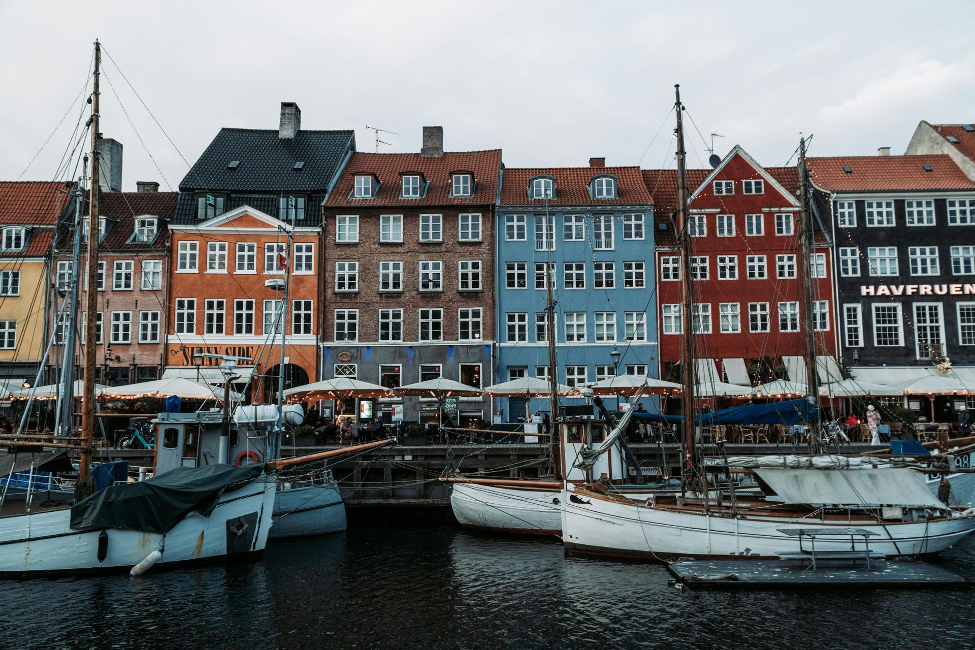 Colorful buildings line a harbor filled with boats in Copenhagen, Denmark.