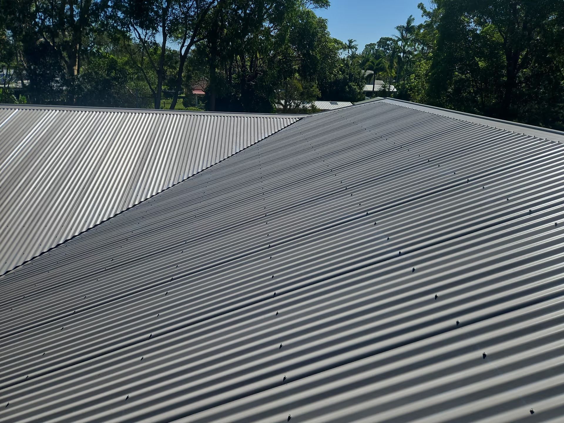 Gray Corrugated Metal Roof With Curved Lines — Over the Top Roofing Specialists in Kunda Park, QLD