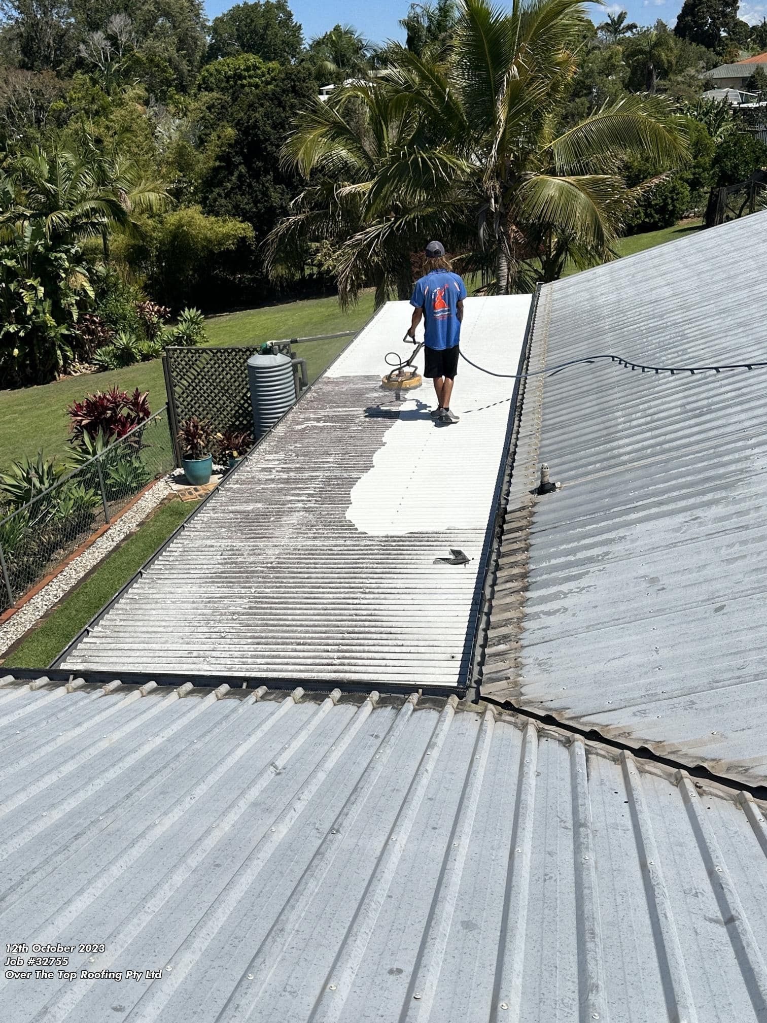Man Applying White Coating to a Metal Roof With a Sprayer — Over the Top Roofing Specialists in Kunda Park, QLD