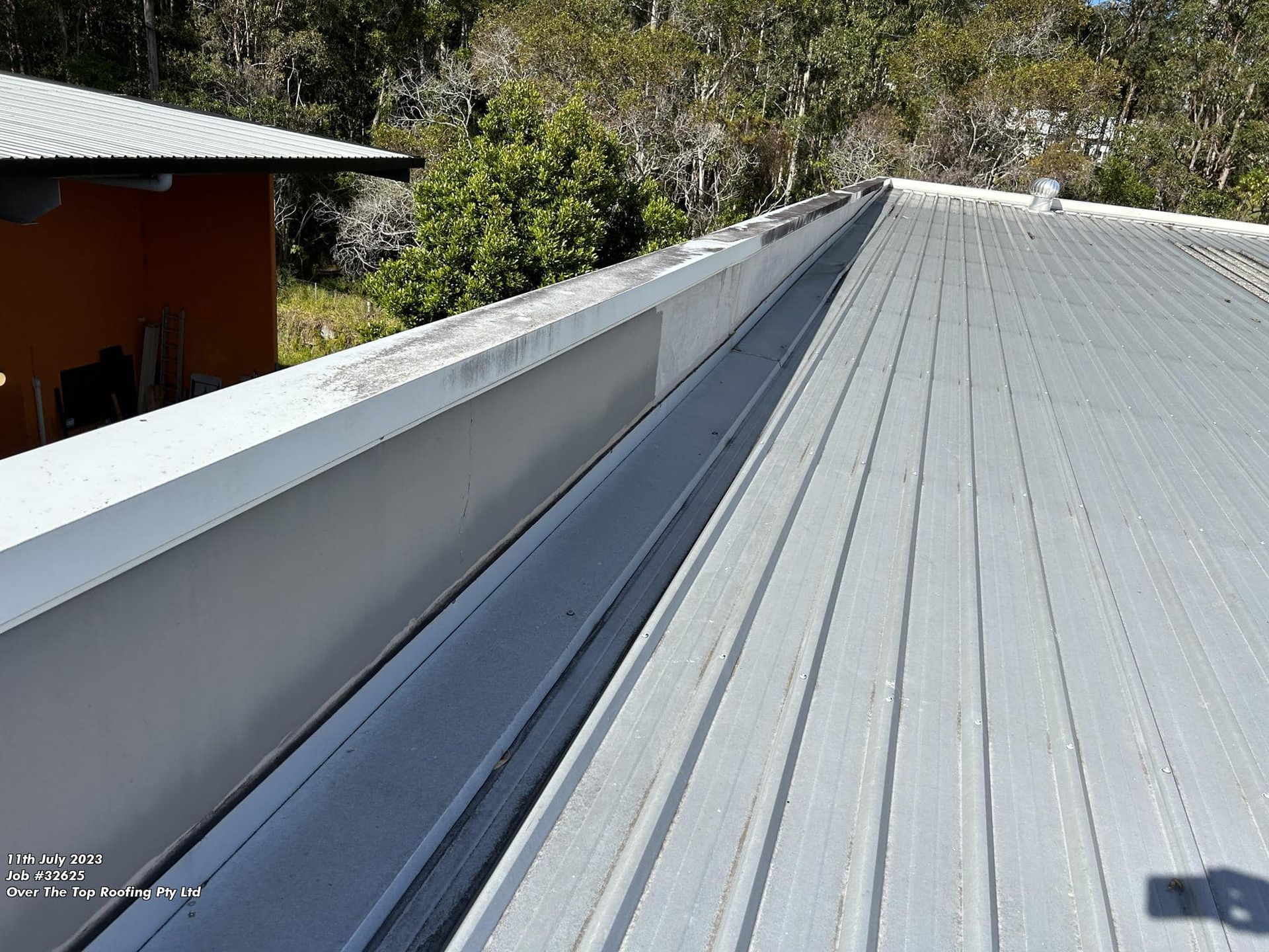 A Metal Roof With an Attached Gutter — Over the Top Roofing Specialists in North Lakes, QLD