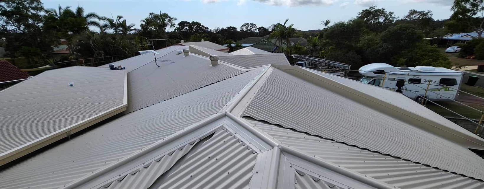 View of a Complex Roof With a White Caravan in the Distance — Over the Top Roofing Specialists in Kunda Park, QLD