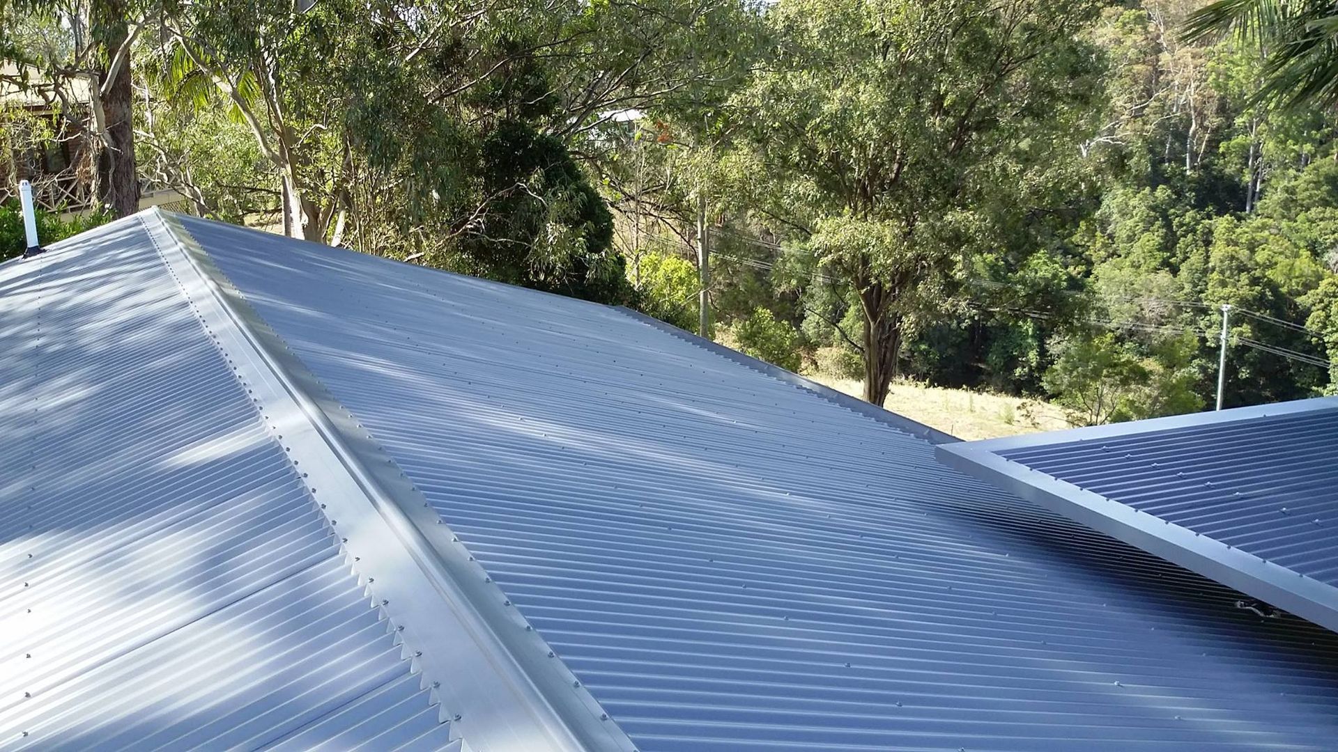 Close-up of a Corrugated Metal Roof, With Trees in the Background — Over the Top Roofing Specialists in Deception Bay, QLD
