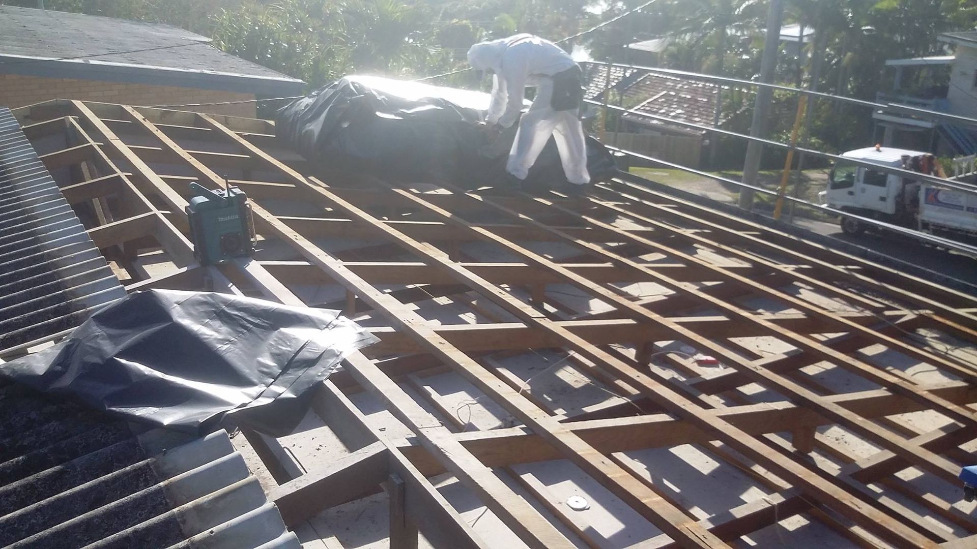 Workers in Protective Suits on a Roof With Exposed Wooden Beams — Over the Top Roofing Specialists in Maroochydore, QLD