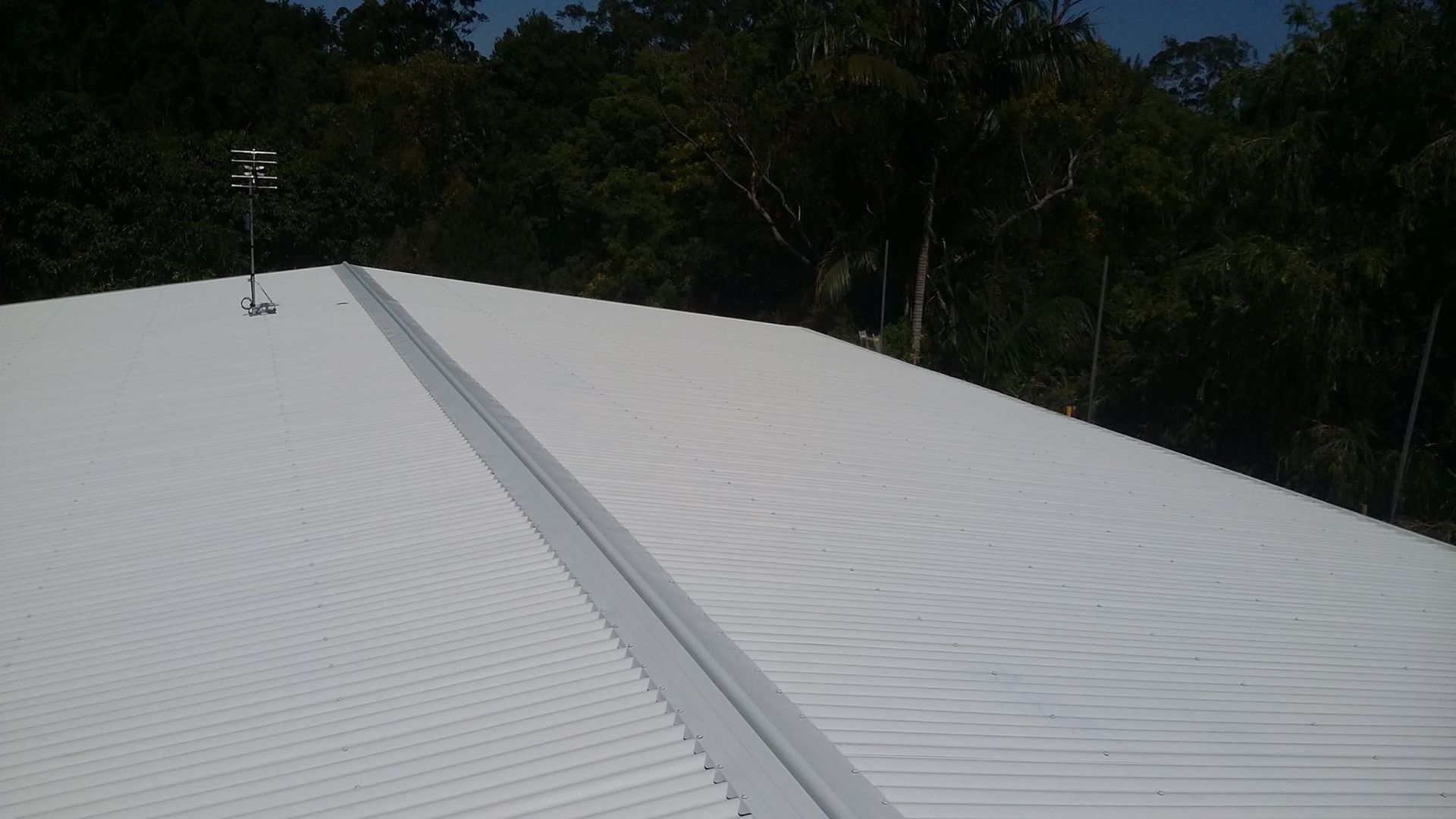 White Metal Roof With a Long Central Drainage Channel — Over the Top Roofing Specialists in Kallangur, QLD