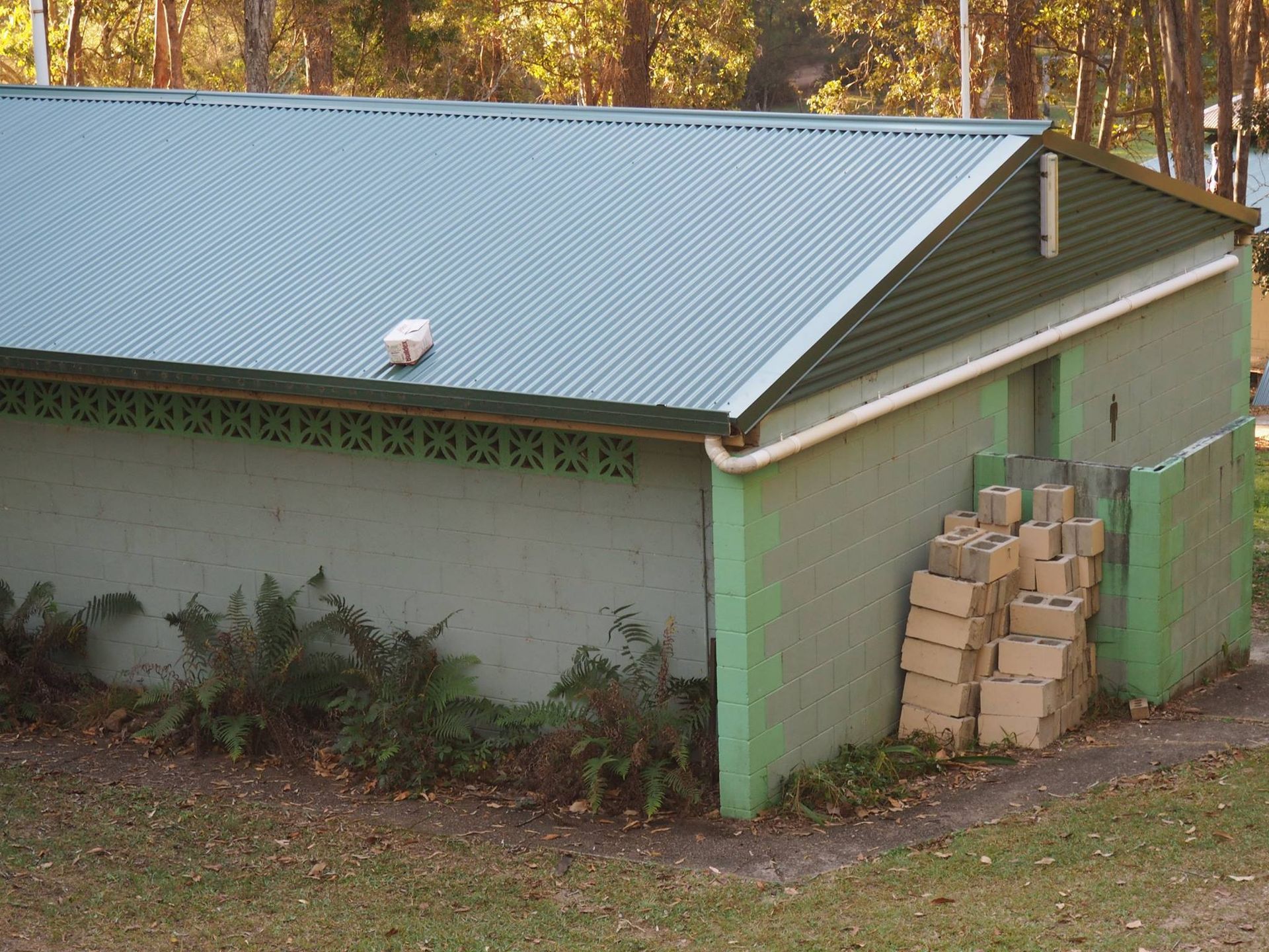 Green Metal-roofed Building With Green Trim and Cinder Blocks — Over the Top Roofing Specialists in Caloundra, QLD