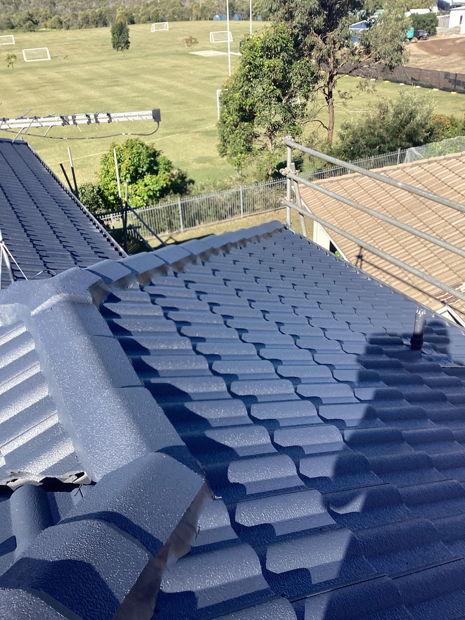 Dark Blue Tiled Rooftop With a View of a Field and a Metal Walkway — Over the Top Roofing Specialists in Kunda Park, QLD