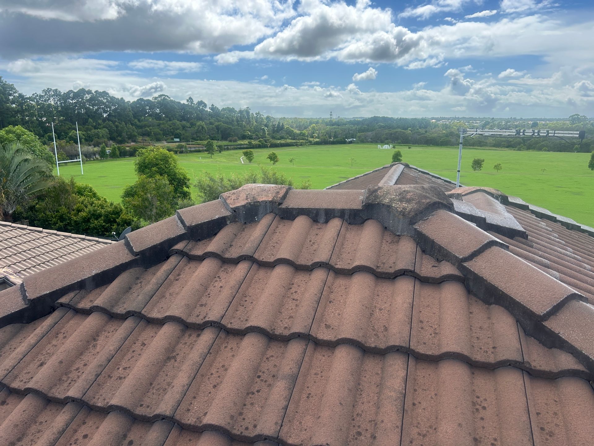 Brown Tile Roof With Debris, Overlooking a Green Field — Over the Top Roofing Specialists in Kunda Park, QLD