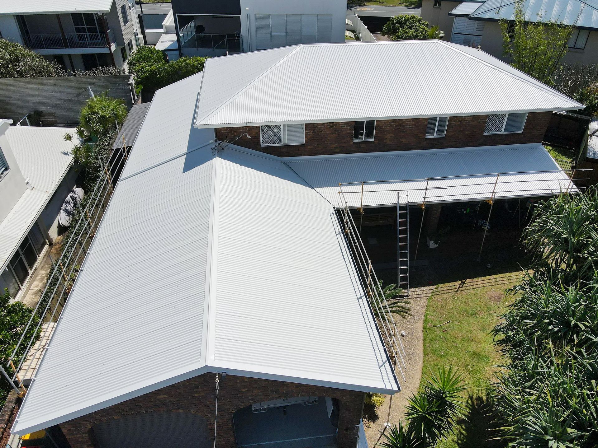 Aerial View of a White Corrugated Metal Roof on a Brick House — Over the Top Roofing Specialists in Kunda Park, QLD