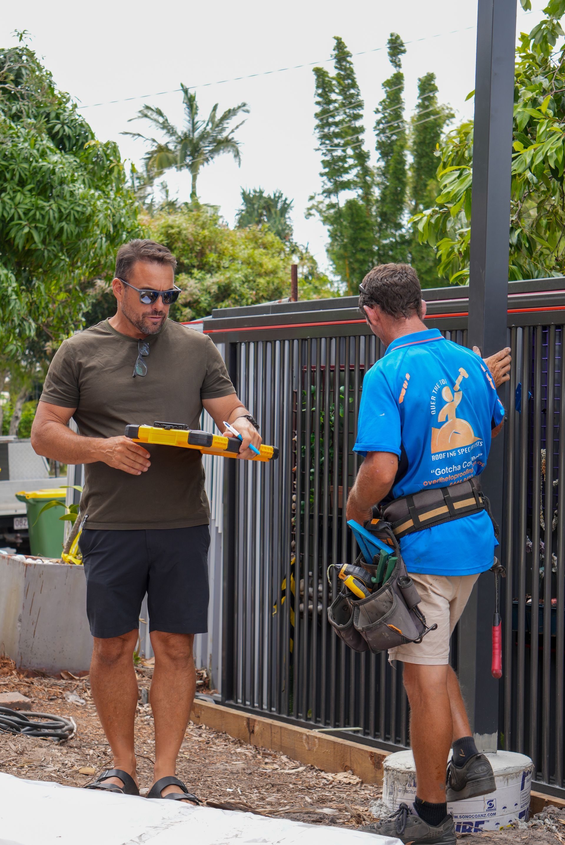 Two Men Inspecting a Metal Fence — Over the Top Roofing Specialists in Kunda Park, QLD