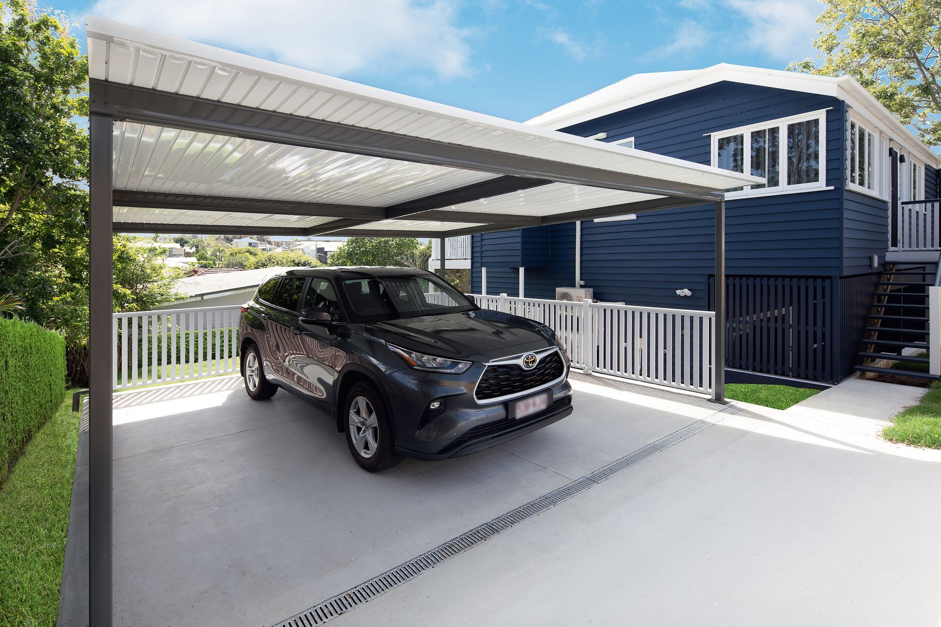 Gray Suv Parked Under a Carport Attached to a Blue House — Over the Top Roofing Specialists in Kunda Park, QLD