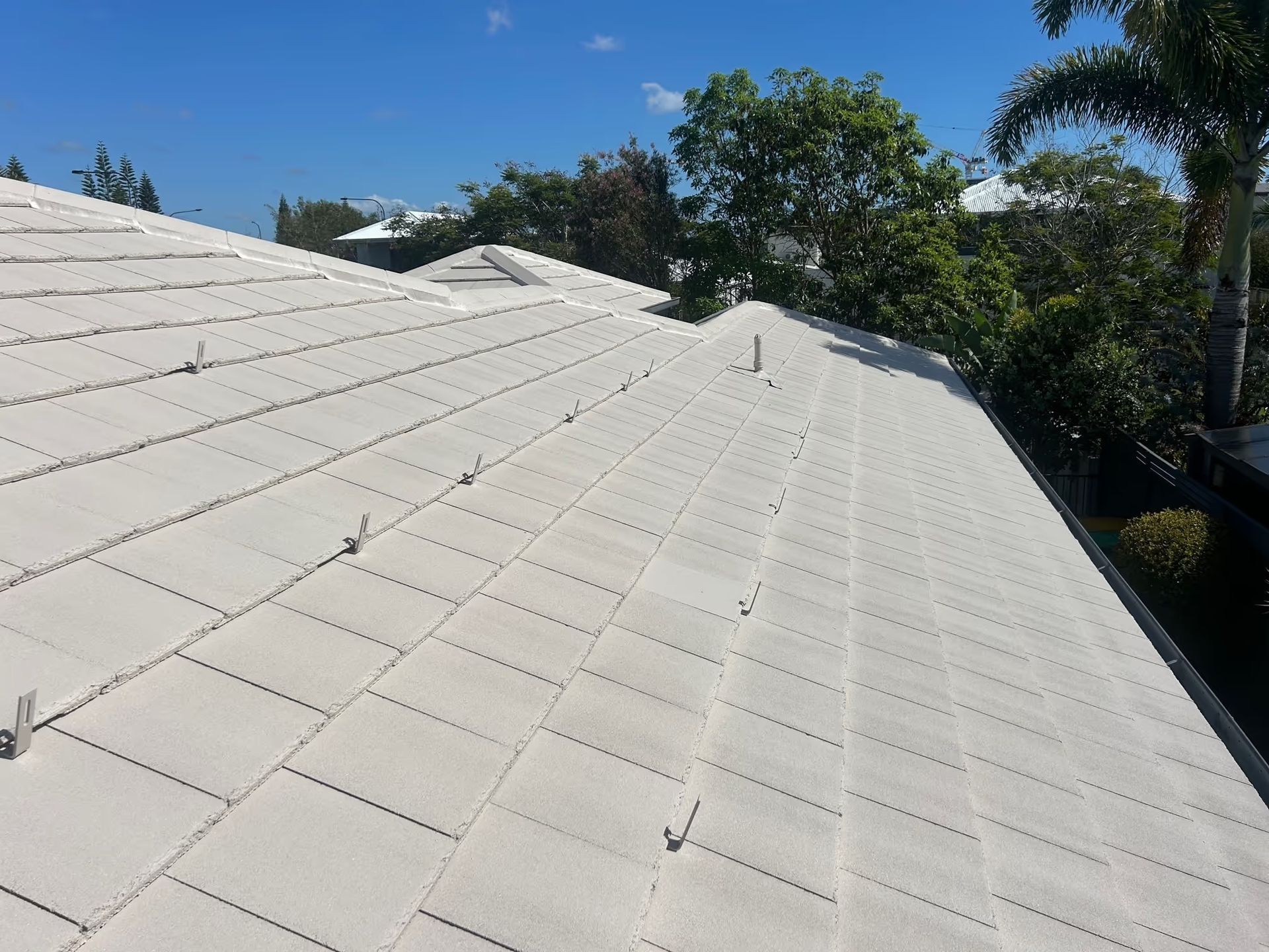 White Tiled Roof on a Sunny Day With Trees in the Background — Over the Top Roofing Specialists in Kunda Park, QLD