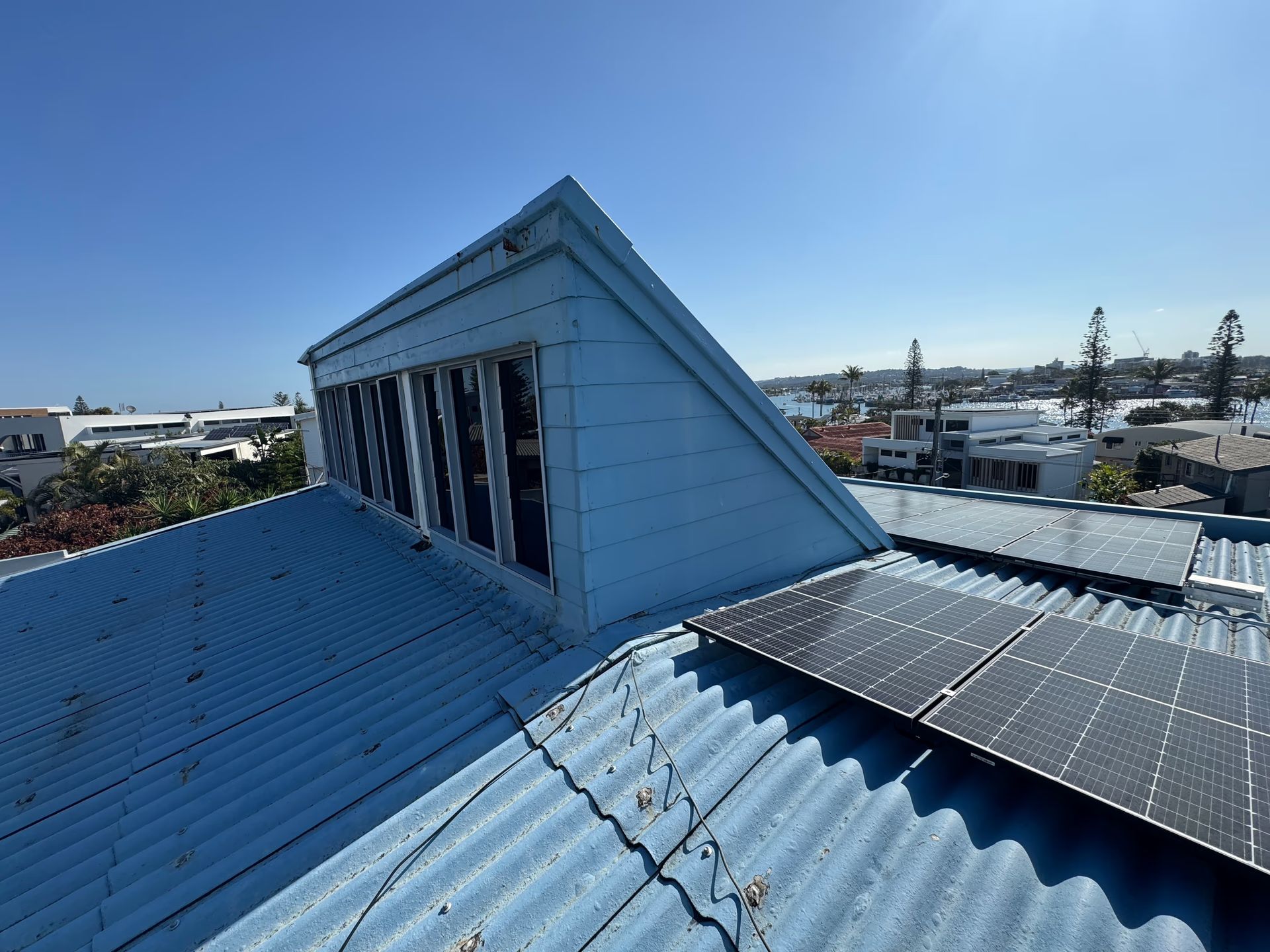 Blue Roof With Solar Panels and a Dormer Window, City and Water View — Over the Top Roofing Specialists in Kunda Park, QLD