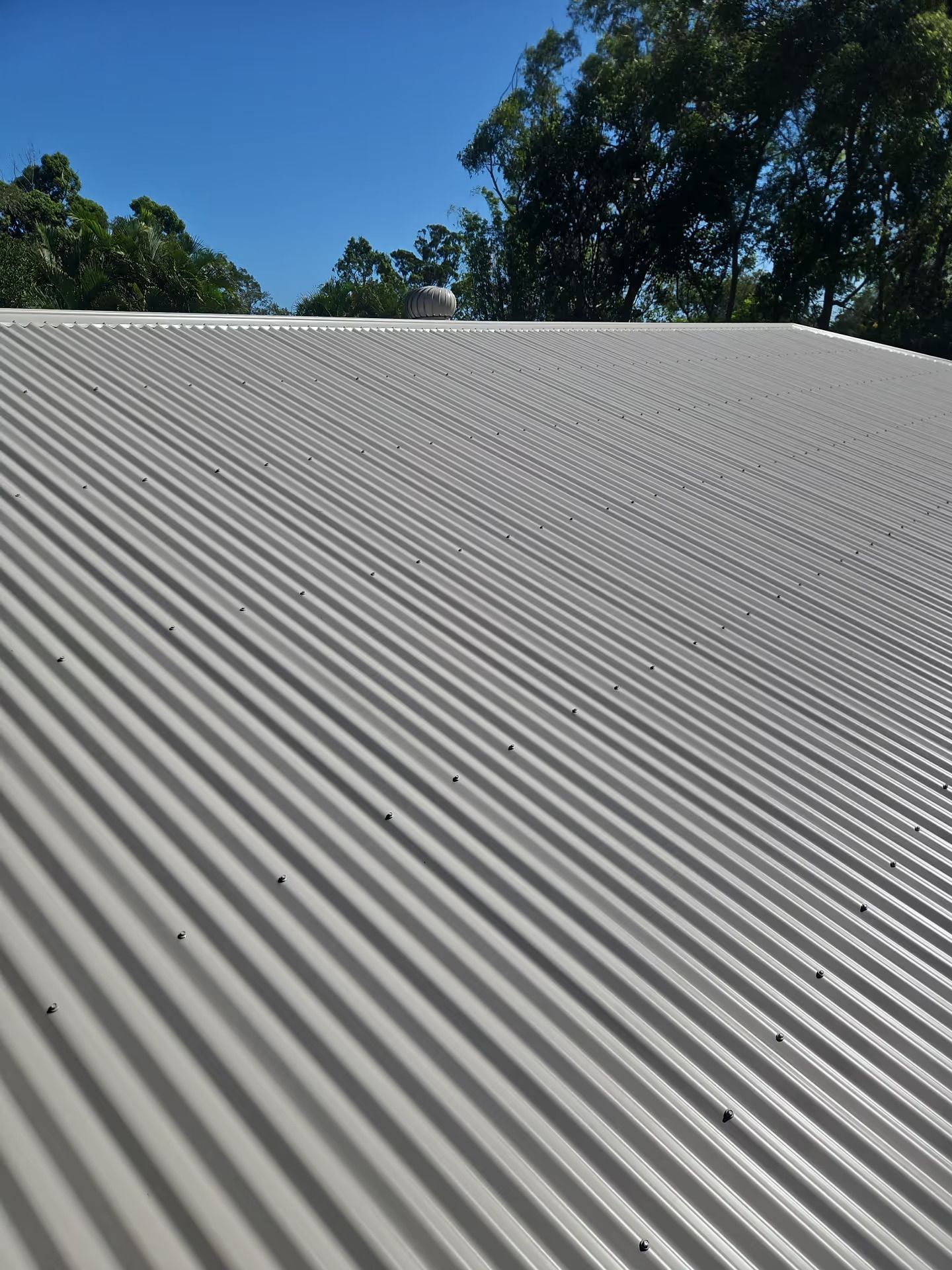 White Corrugated Metal Roof Under a Blue Sky — Over the Top Roofing Specialists in Kunda Park, QLD