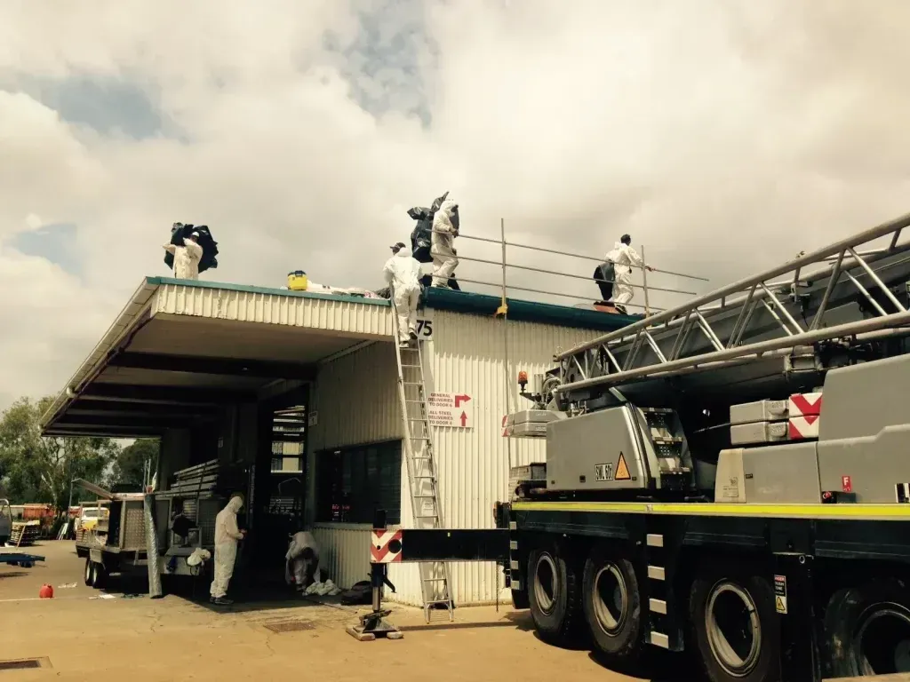 Workers in Protective Suits on a Roof, Near a Crane, and Scaffolding — Over the Top Roofing Specialists in North Lakes, QLD