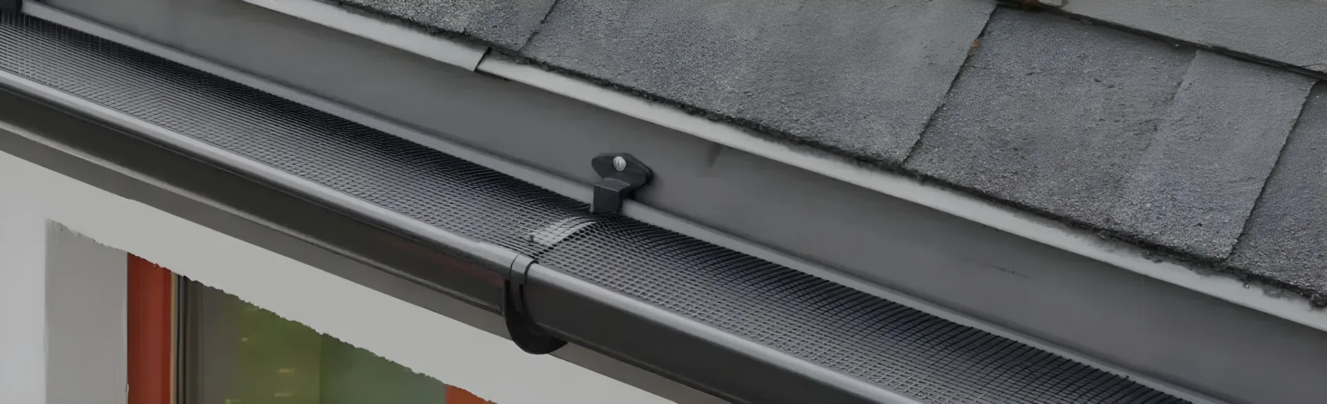 Close-up of a Dark Gray Rain Gutter With a Screen Attached to the Roof — Over the Top Roofing Specialists in Kallangur, QLD