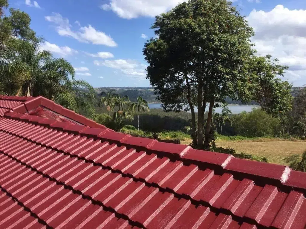 Red Tiled Roof With a Scenic View of Trees, Water, and Blue Sky — Over the Top Roofing Specialists in Gympie, QLD