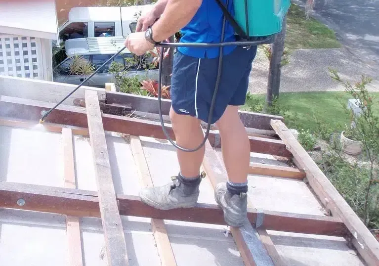 Person Spraying a Roof With a Backpack Sprayer — Over the Top Roofing Specialists in Maroochydore, QLD