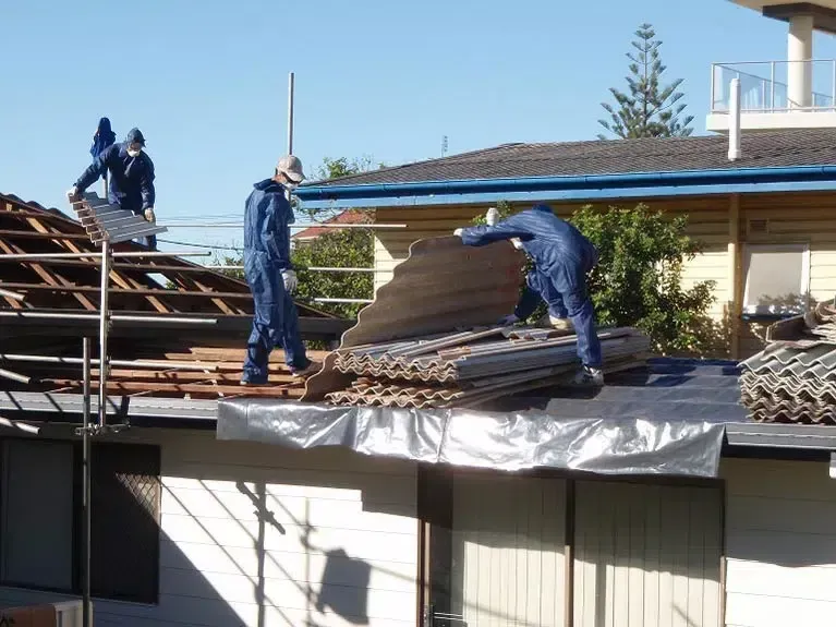 Workers in Blue Coveralls Remove Old Roofing Material — Over the Top Roofing Specialists in Narangba, QLD
