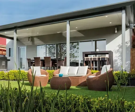Outdoor Patio With Seating on Green Grass, Next to a Modern Building — Over the Top Roofing Specialists in Deception Bay, QLD