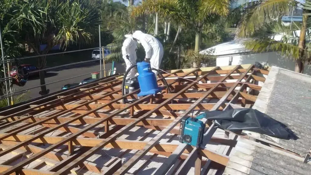 Two Workers in Protective Suits on a Roof, Using a Vacuum — Over the Top Roofing Specialists in Kallangur, QLD