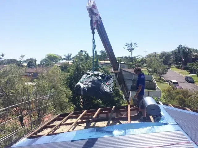 Crane Lifting Materials Onto a Roof Under Construction — Over the Top Roofing Specialists in Gympie, QLD