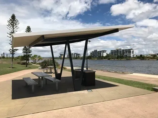 Picnic Shelter With Picnic Table, Trash Can, and Buildings — Over the Top Roofing Specialists in Caloundra, QLD