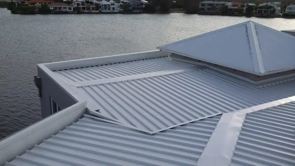 White Metal Roof With a Water View and a Square Peaked Section — Over the Top Roofing Specialists in North Lakes, QLD