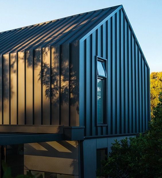 Grey Metal-clad Modern House With a Gabled Roof and a Small Window — Over the Top Roofing Specialists in Kunda Park, QLD