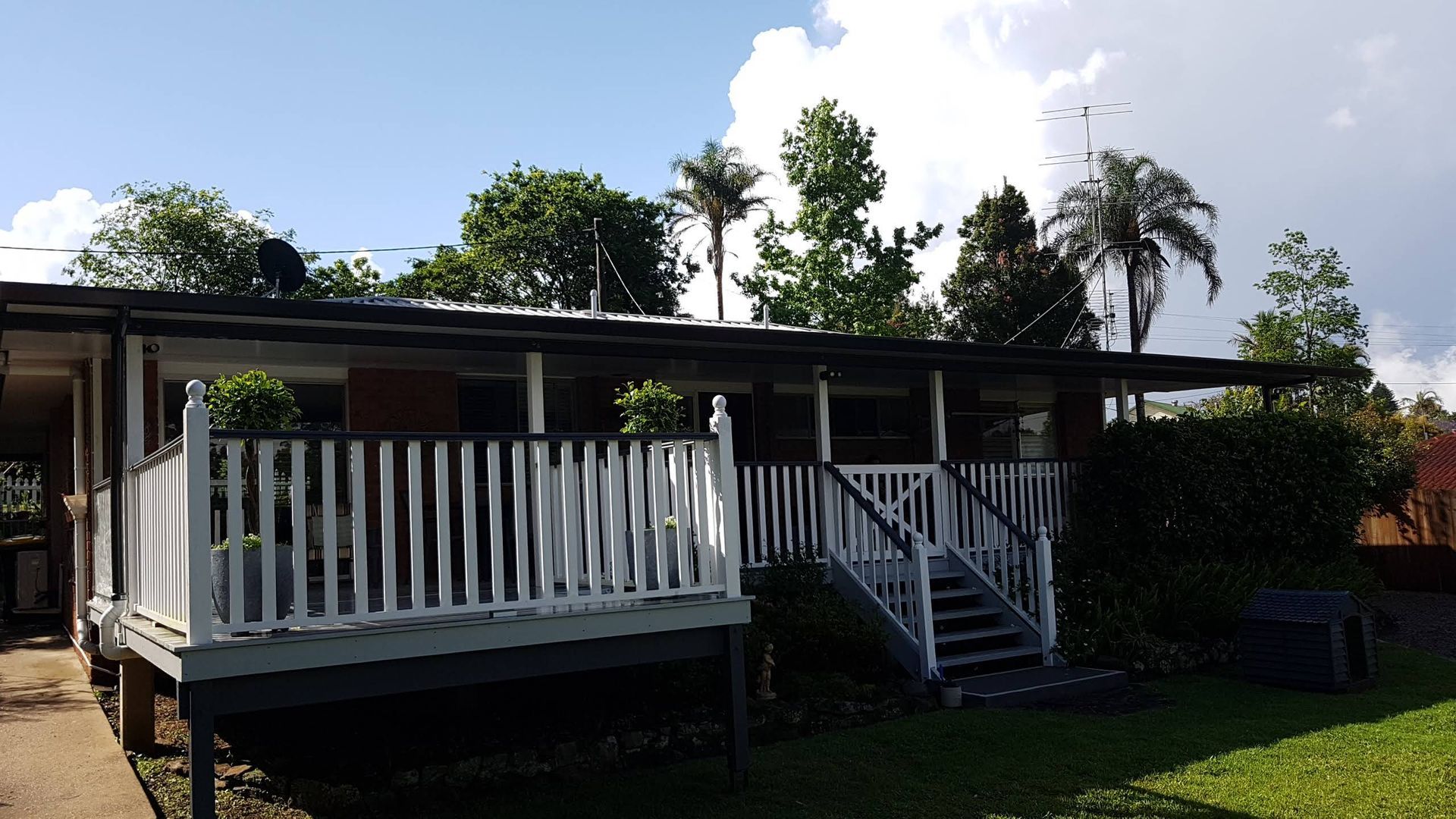 Low-set House With White Deck and Steps, Surrounded by Green Trees — Over the Top Roofing Specialists in Maroochydore, QLD
