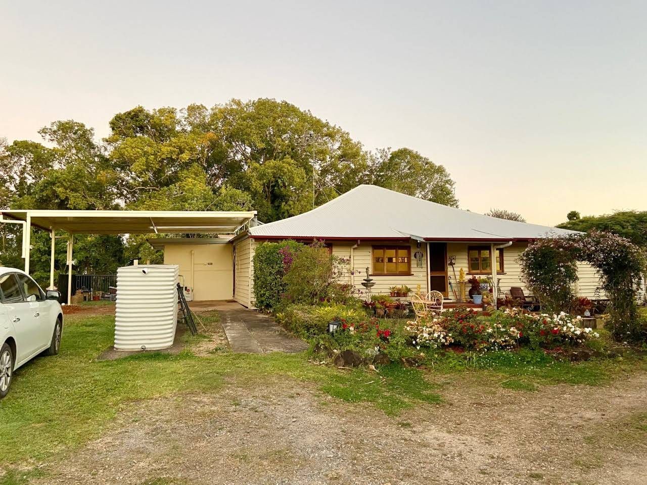 Light-colored House With Attached Carport and Garage, Garden in Front — Over the Top Roofing Specialists in Maroochydore, QLD