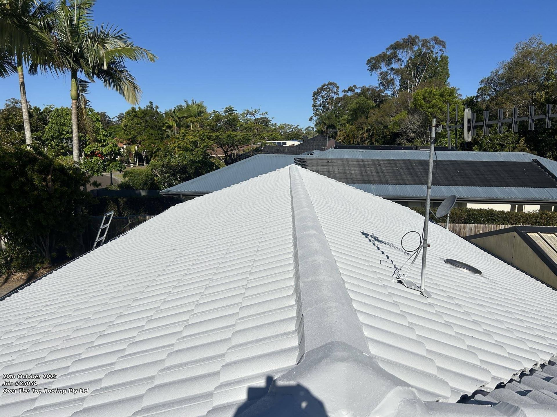 White Tiled Roof With Central Ridge, Antenna, Trees, and Blue Sky — Over the Top Roofing Specialists in Gympie, QLD
