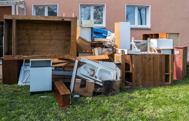 A pile of junk is sitting in the grass in front of a house.