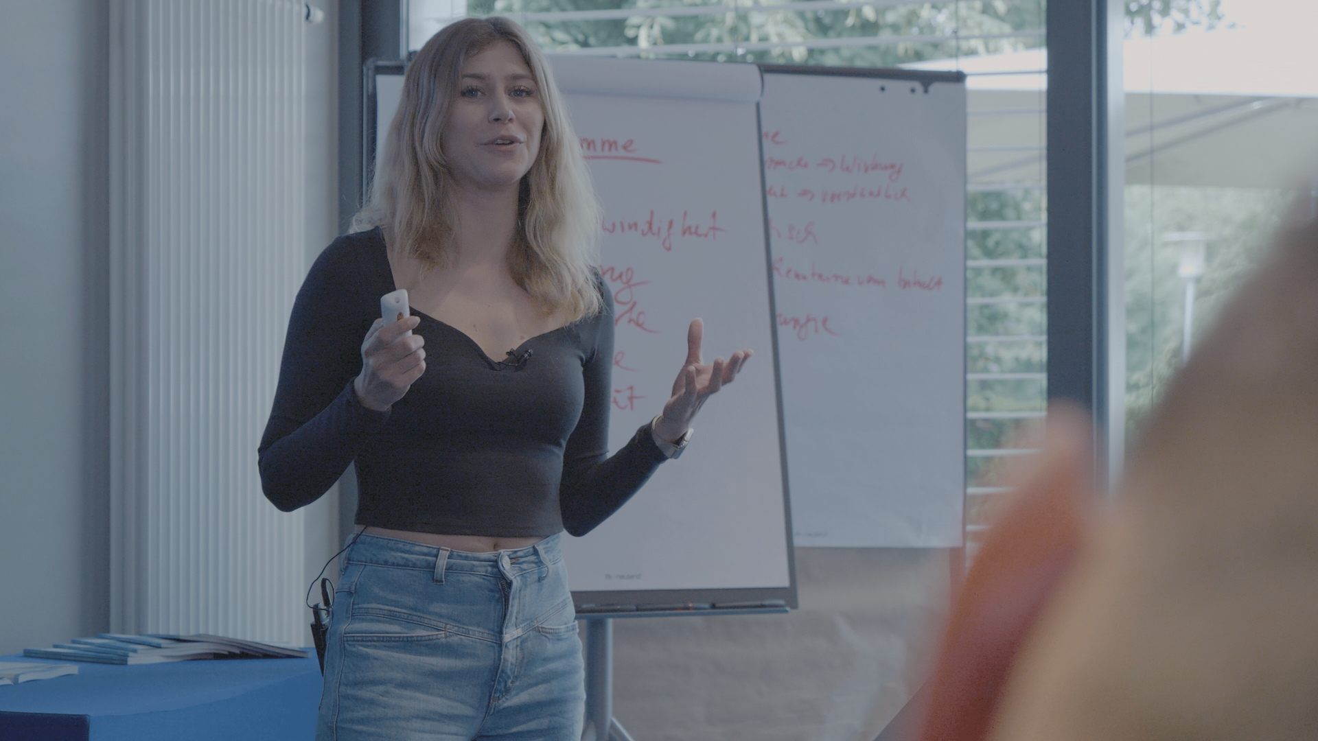 Eine Frau hält in einem Klassenzimmer vor einem Whiteboard eine Präsentation.