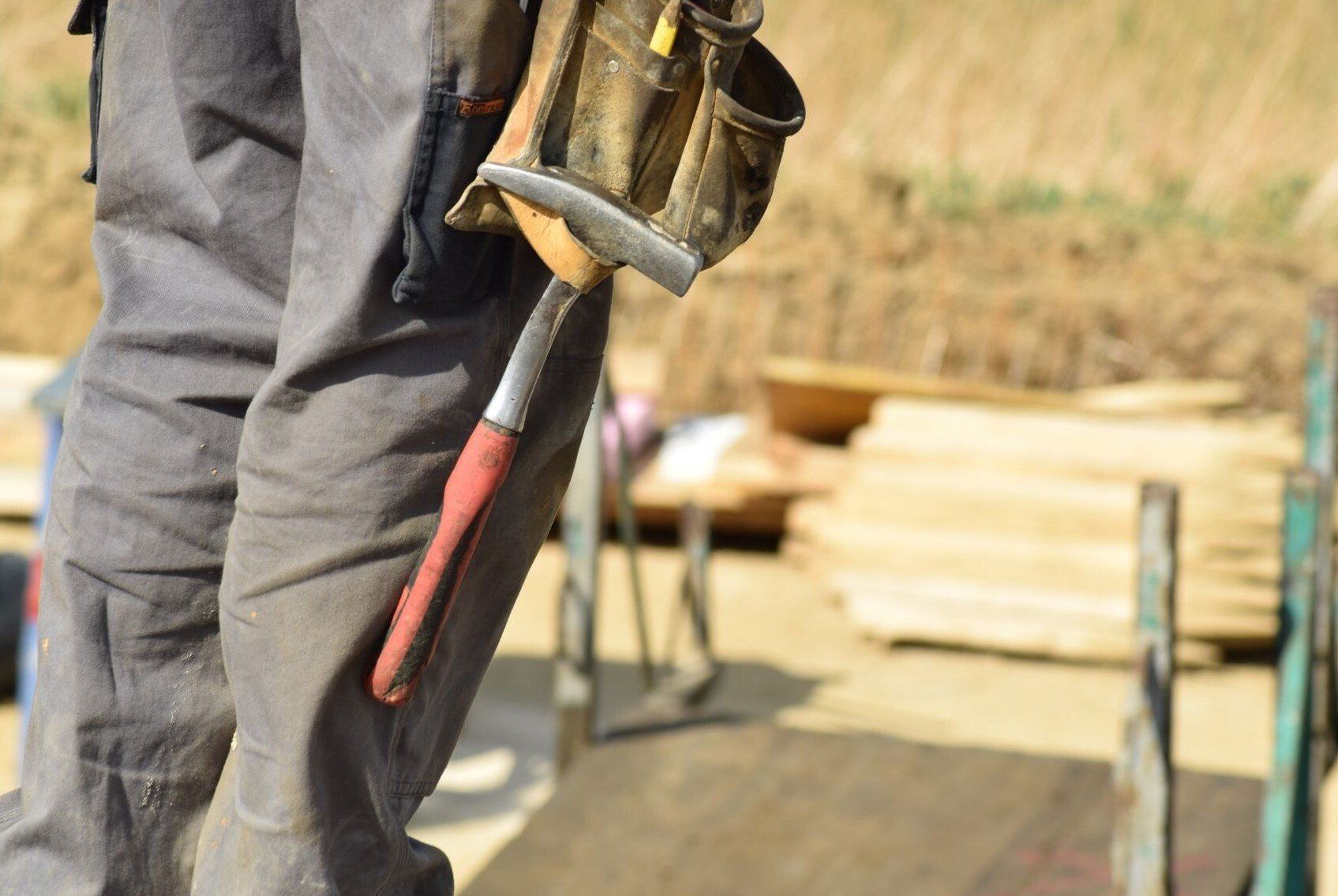 Delta Construction contractor standing over lumber wearing a tool belt