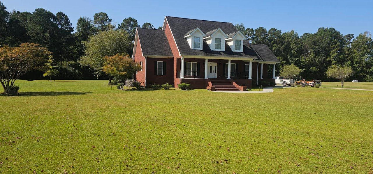 A dark, rounded shrub sits on a concrete driveway corner next to a brick house with an open garage and address 533.