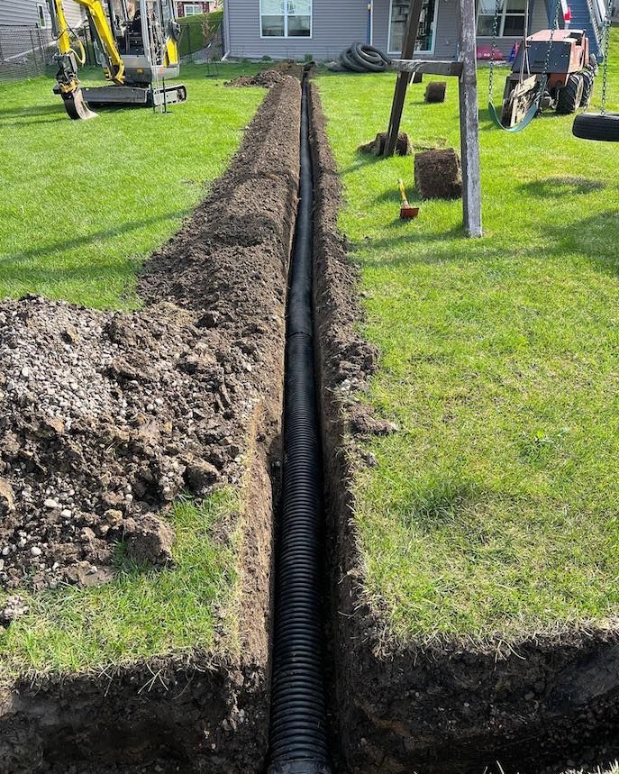 A yellow excavator is sitting on top of a pile of gravel.