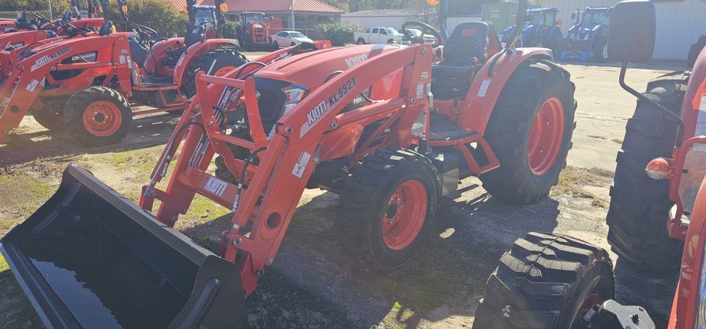 An orange Kubota tractor with a front-end loader parked in an outdoor equipment lot.