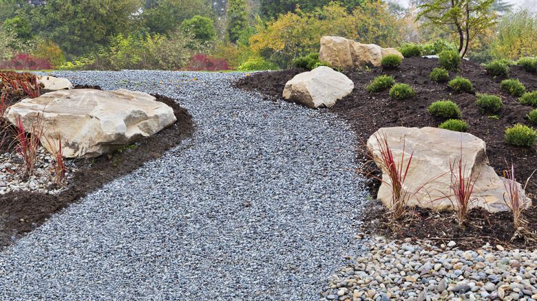 A yellow excavator is sitting on top of a pile of gravel.