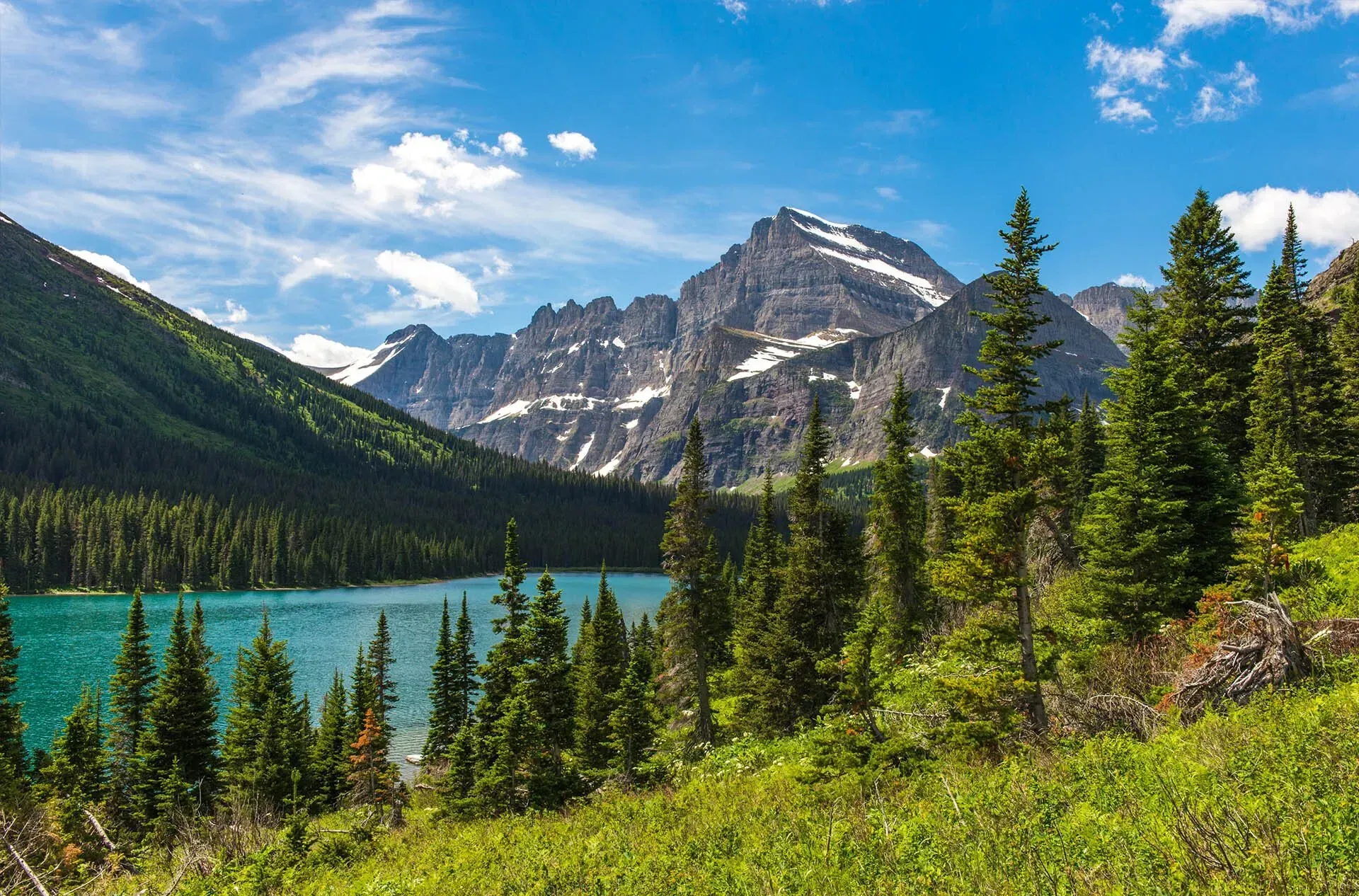 A lake surrounded by mountains and trees with a mountain in the background.