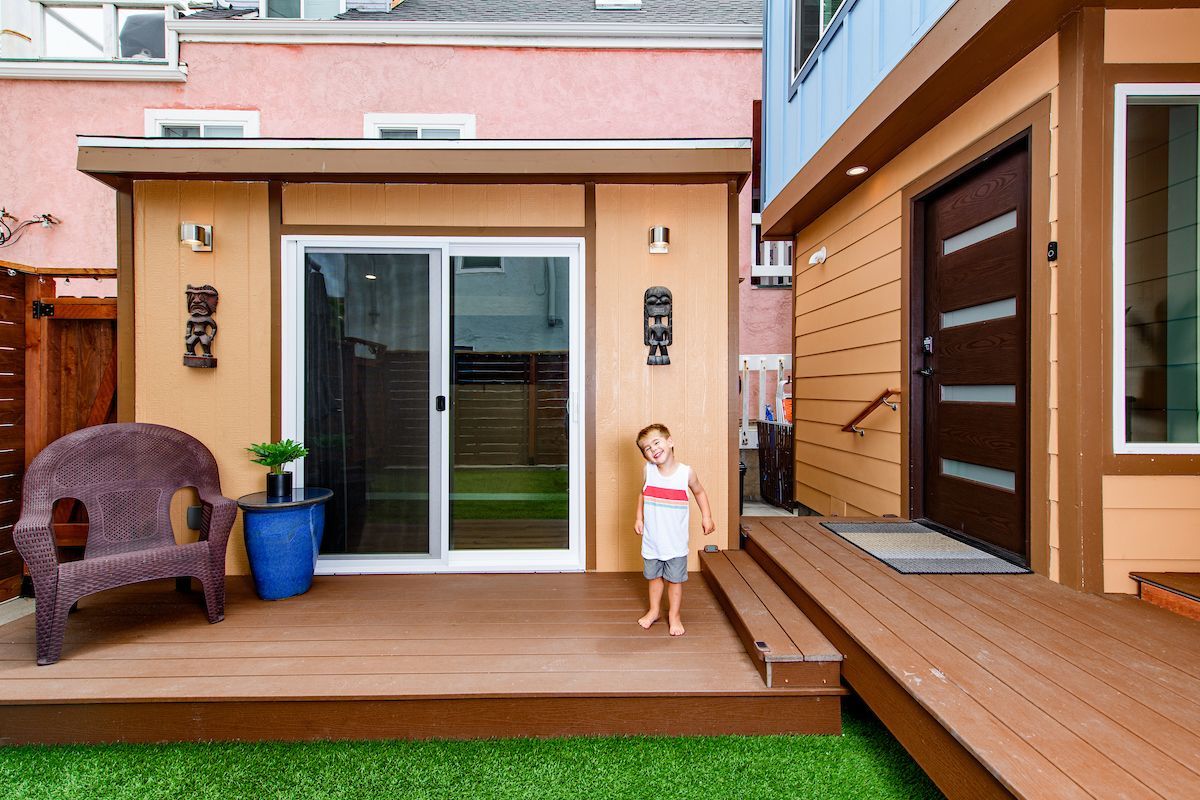 A little girl standing on a deck in front of a house