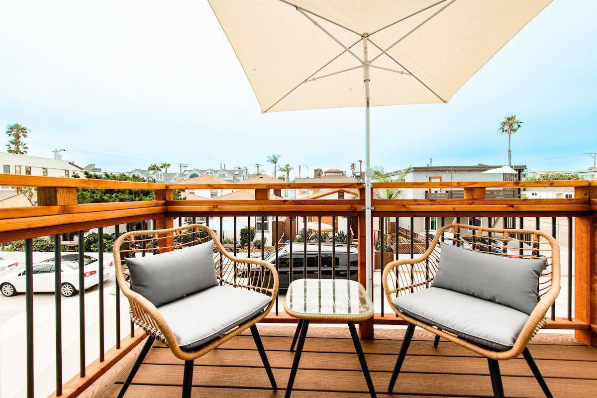 A balcony with two chairs , a table and an umbrella.