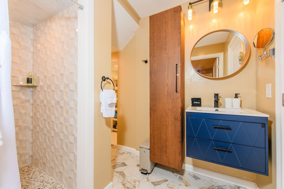 A bathroom with a sink , mirror and walk in shower.