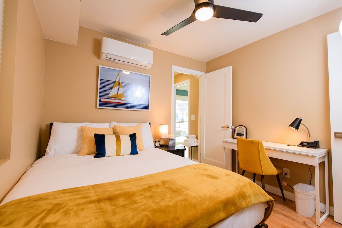 A bedroom with a bed , desk , chair and ceiling fan.