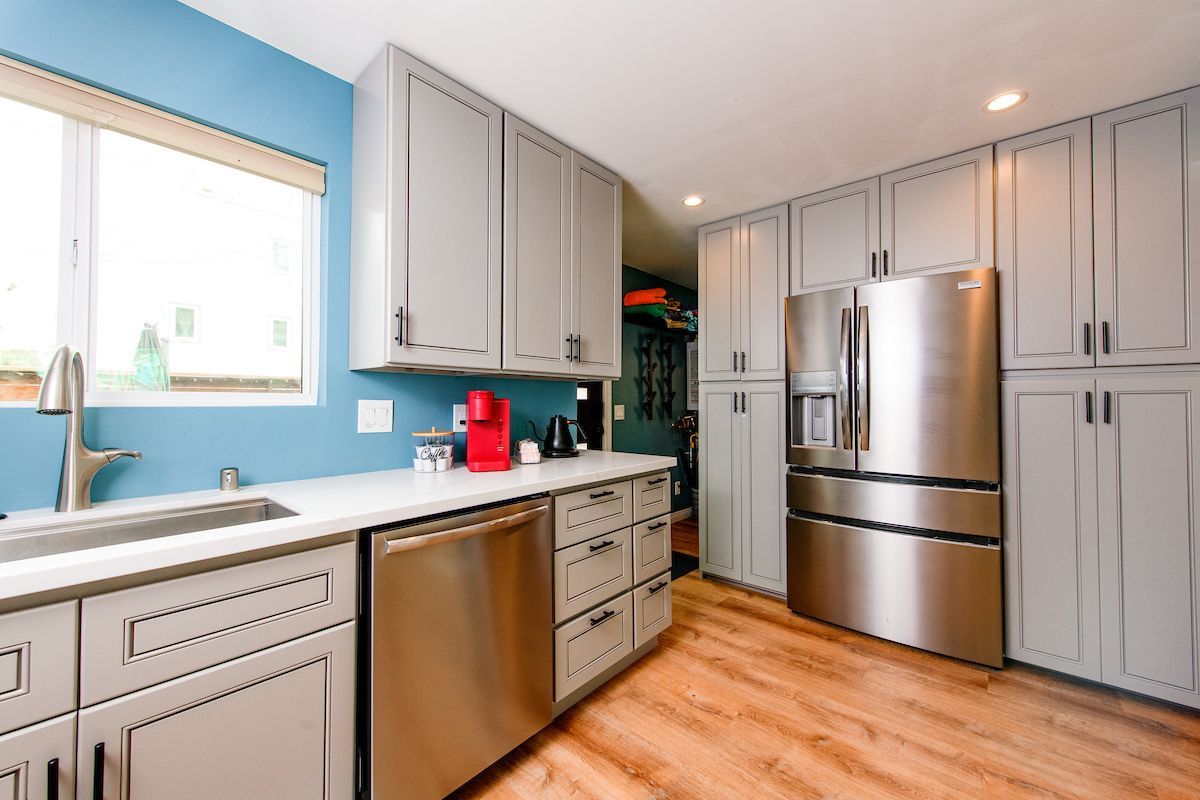 A kitchen with stainless steel appliances and gray cabinets.