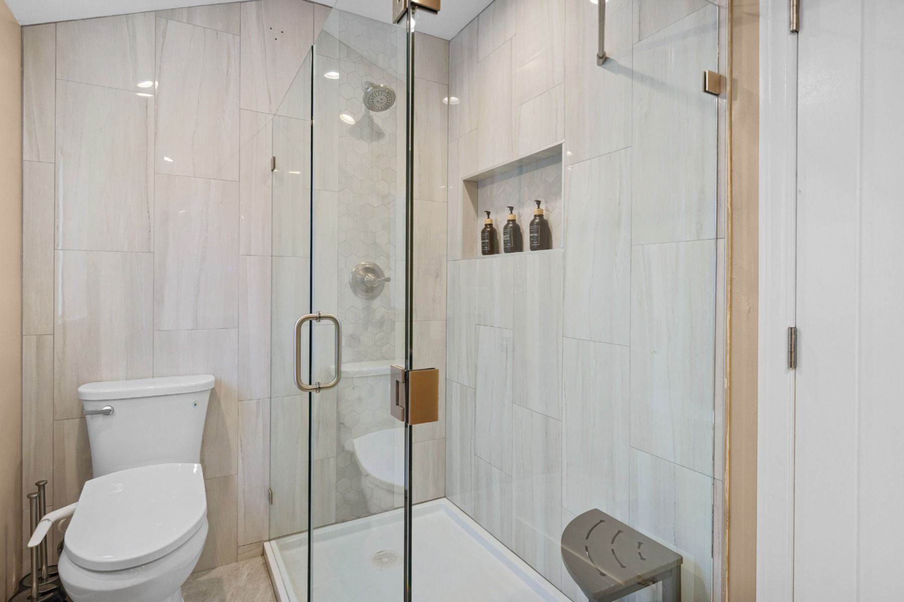 A bathroom with a toilet , shower , and cabinet.