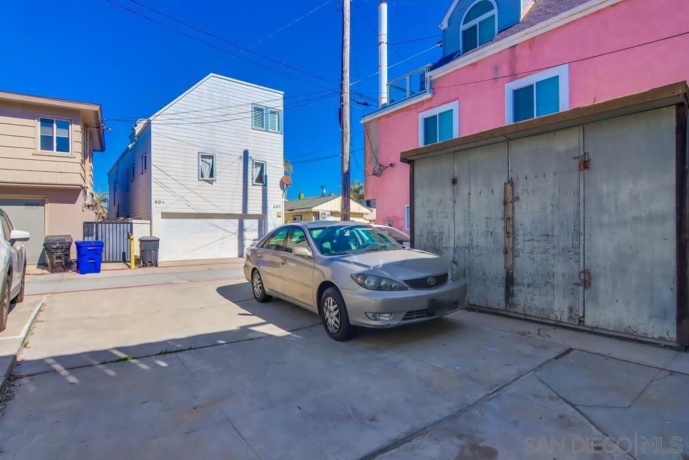 A car is parked in a parking lot in front of a pink building.
