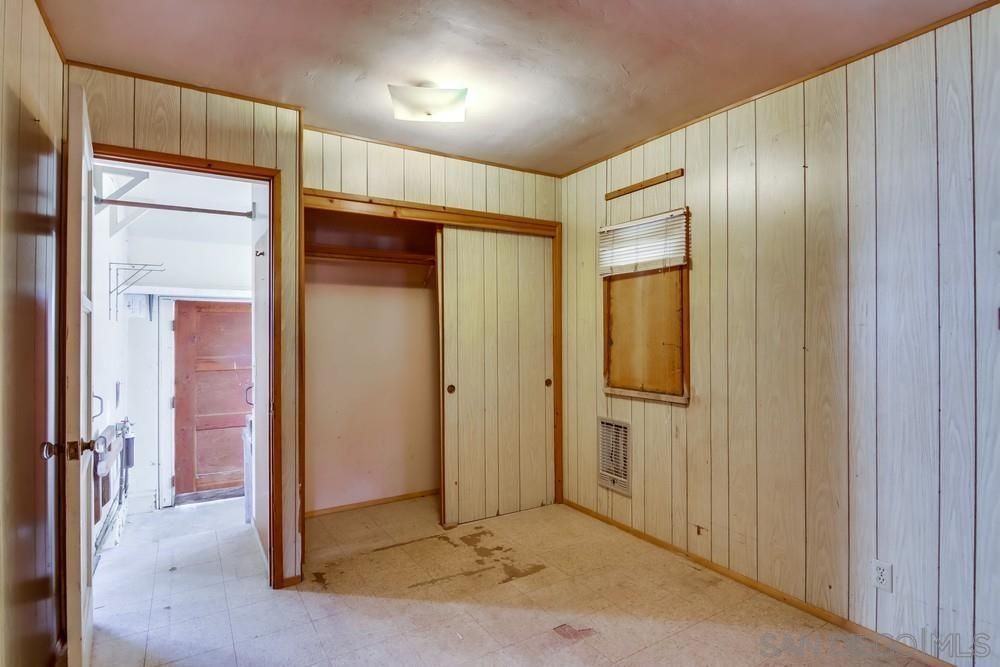 An empty room with wood paneling and a window.