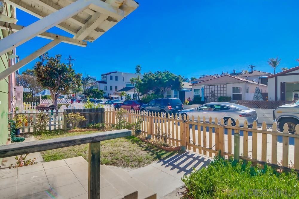 A wooden fence surrounds a yard with cars parked in front of it.